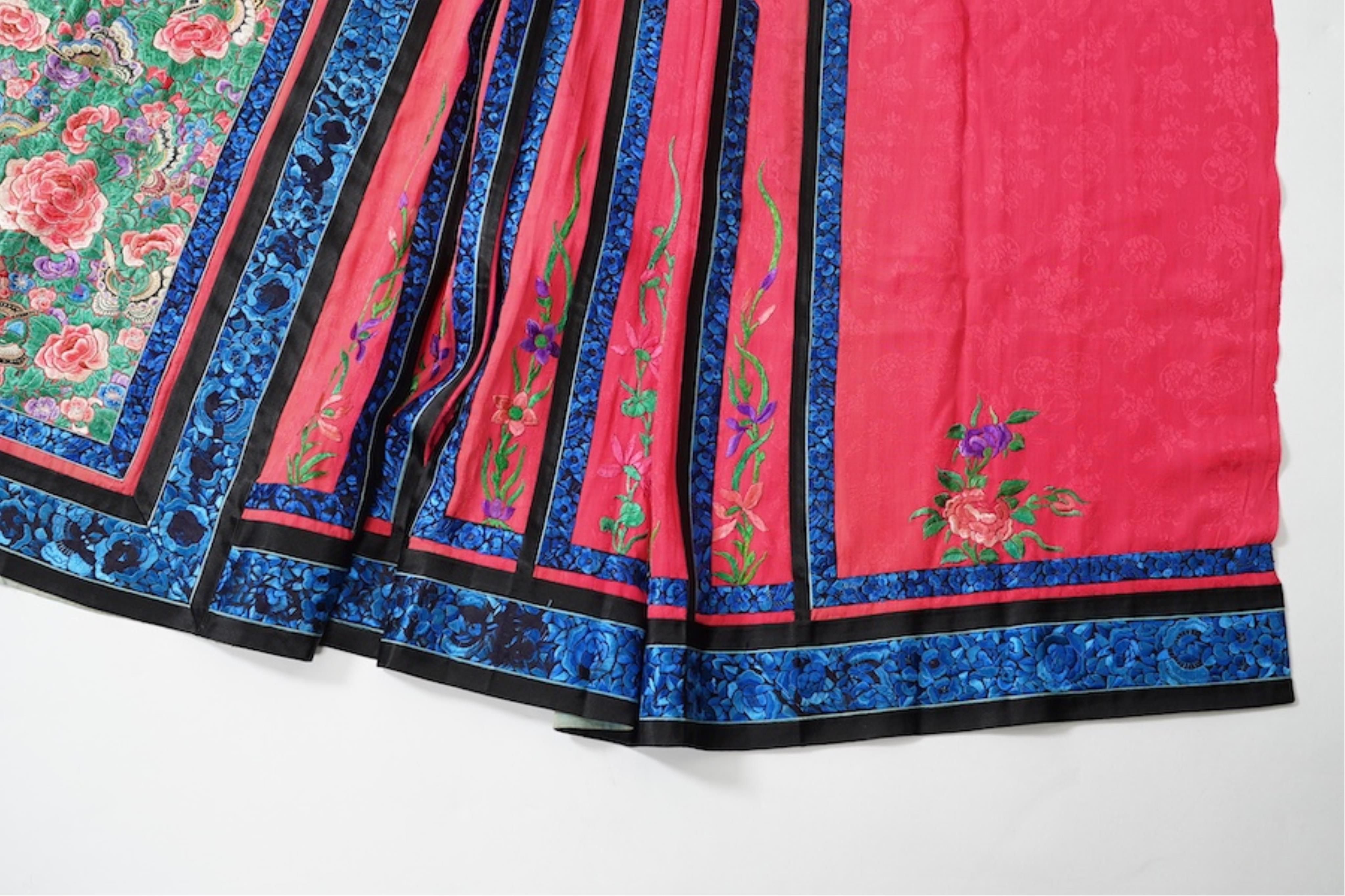 Two late 19th early 20th century Chinese wedding skirts. Made with pink silk damask, embroidered with large decorative silk floral and butterfly front panels bordered by blue embroidered black silk borders between pleats